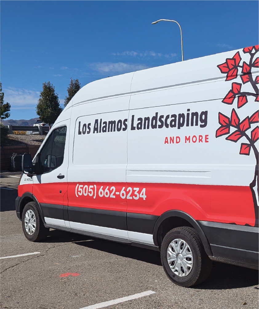 A white van with a red and black design featuring the text 'Los Alamos Landscaping and More' along with a red tree graphic on the side. The van also displays a phone number, '(505) 662-6234,' in bold white text over a red stripe.