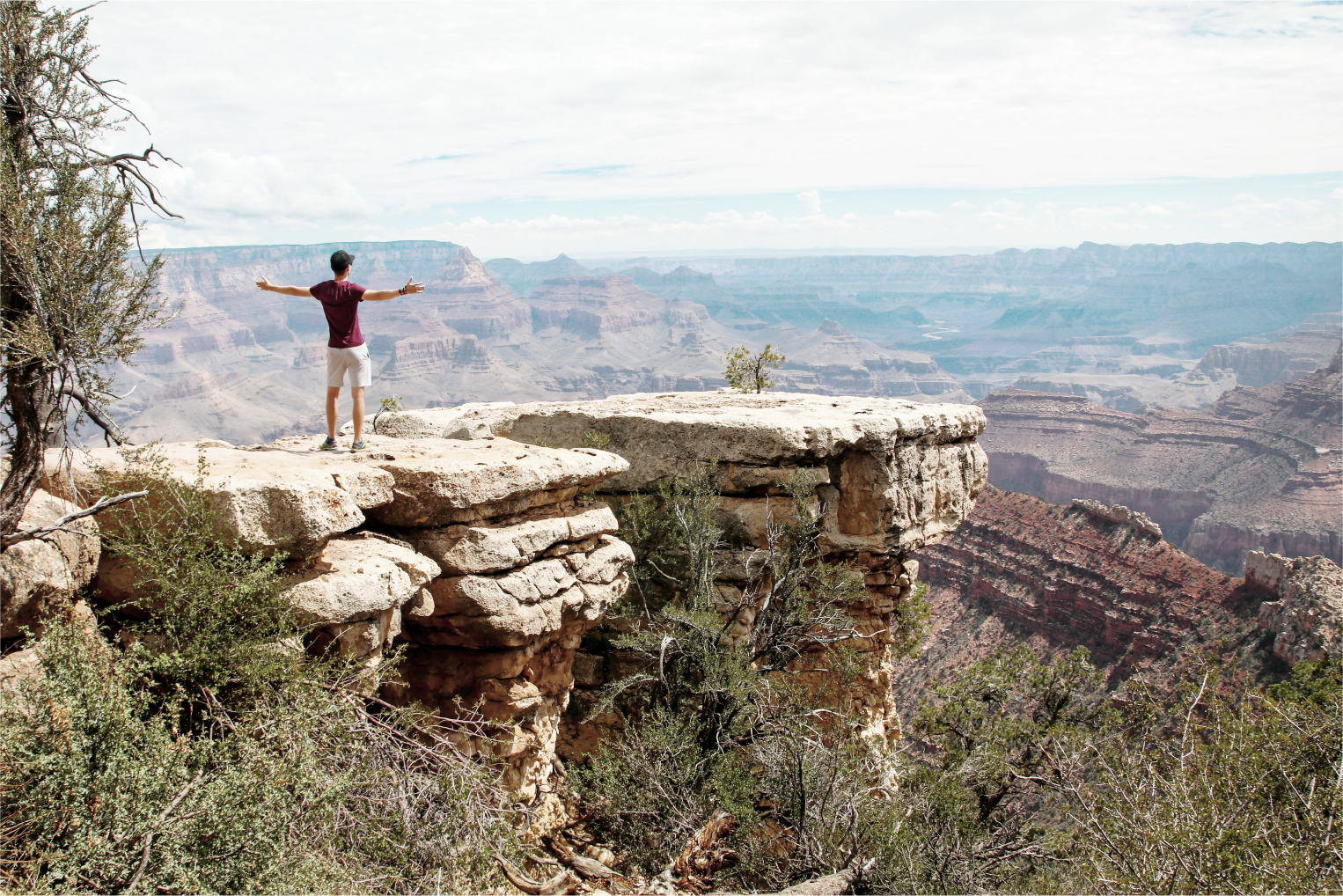 Person standing arms spread at the edge of the grand canyon