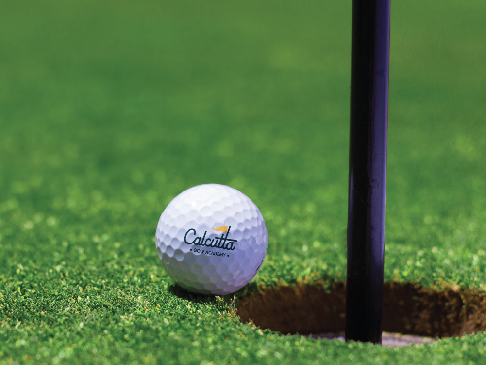 Calcutta branded golf ball going into hole.