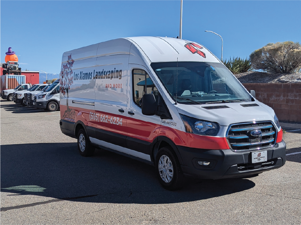 Front view of Los Alamos Landscaping & More’s Transit van with custom wrap, showcasing the company logo and bold red accents on the lower bumper.