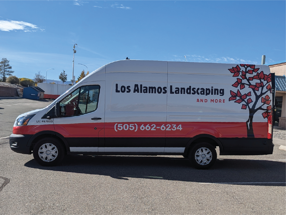 Left side view of Los Alamos Landscaping & More’s Transit van, with clear branding including the company name, phone number, and red tree graphic for an eye-catching design.